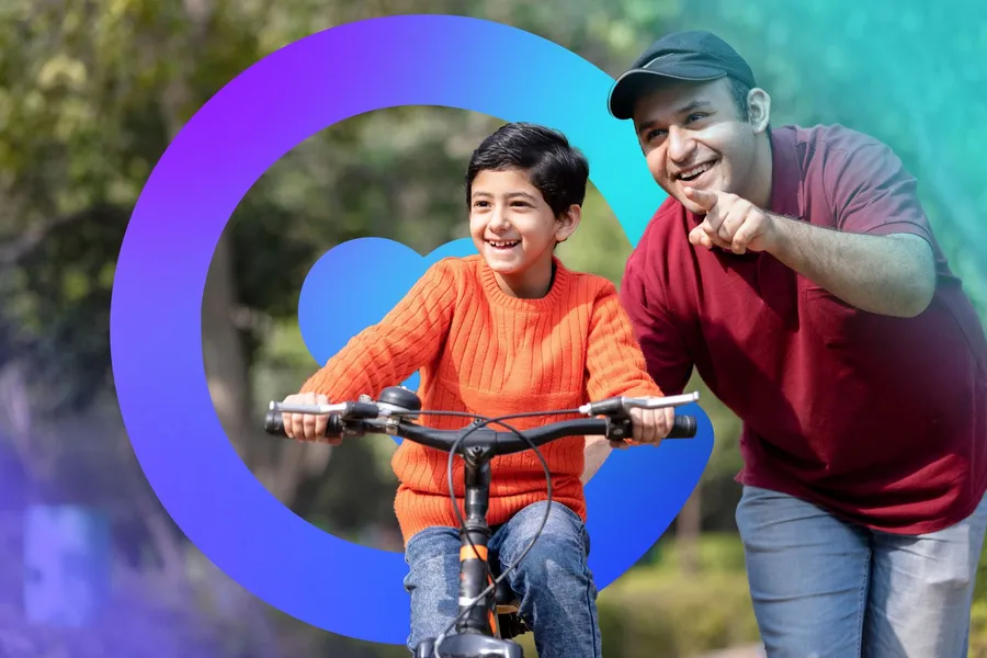 A father cheering on his son riding a bike through the park, framed by the Catilize C